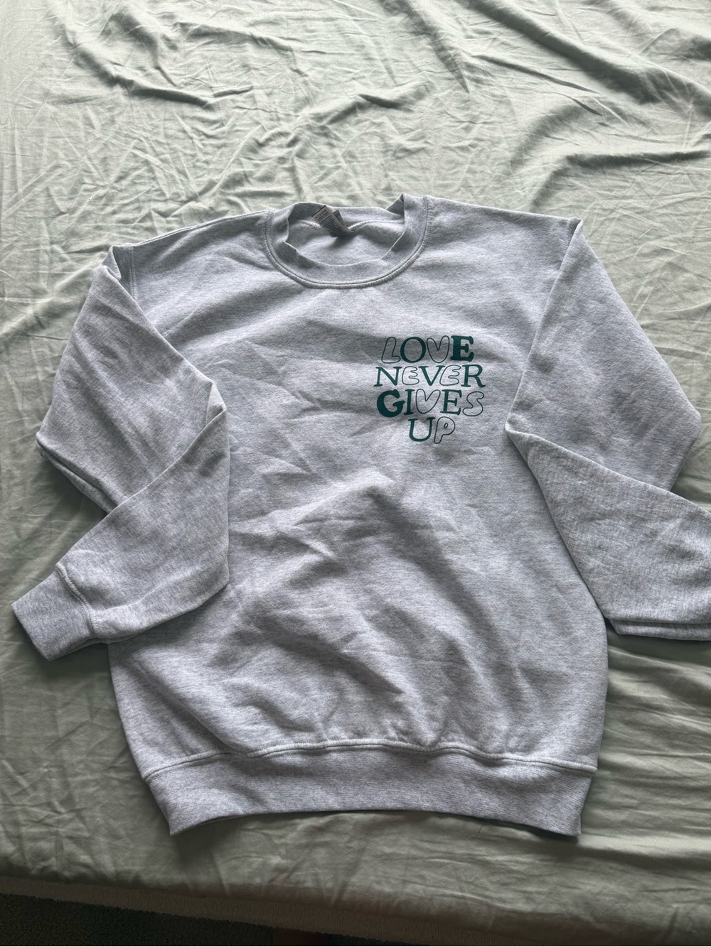 Grey Crewneck Sweatshirt with 'Love Never Gives Up' Graphic